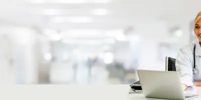 A woman doctor smiling and looking at her computer